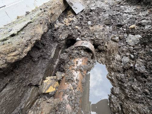 Open excavation showing a damaged drain pipe